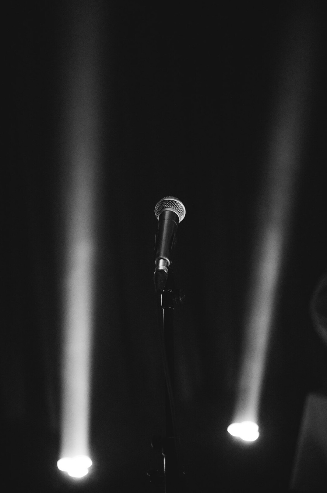 Dramatic stage spotlight and microphone on a dark concert stage
